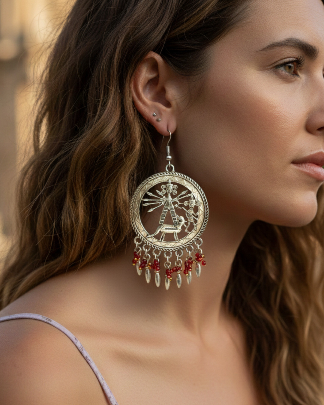 Boho-style storytelling earrings in silver with red beads and dangling metal teardrops